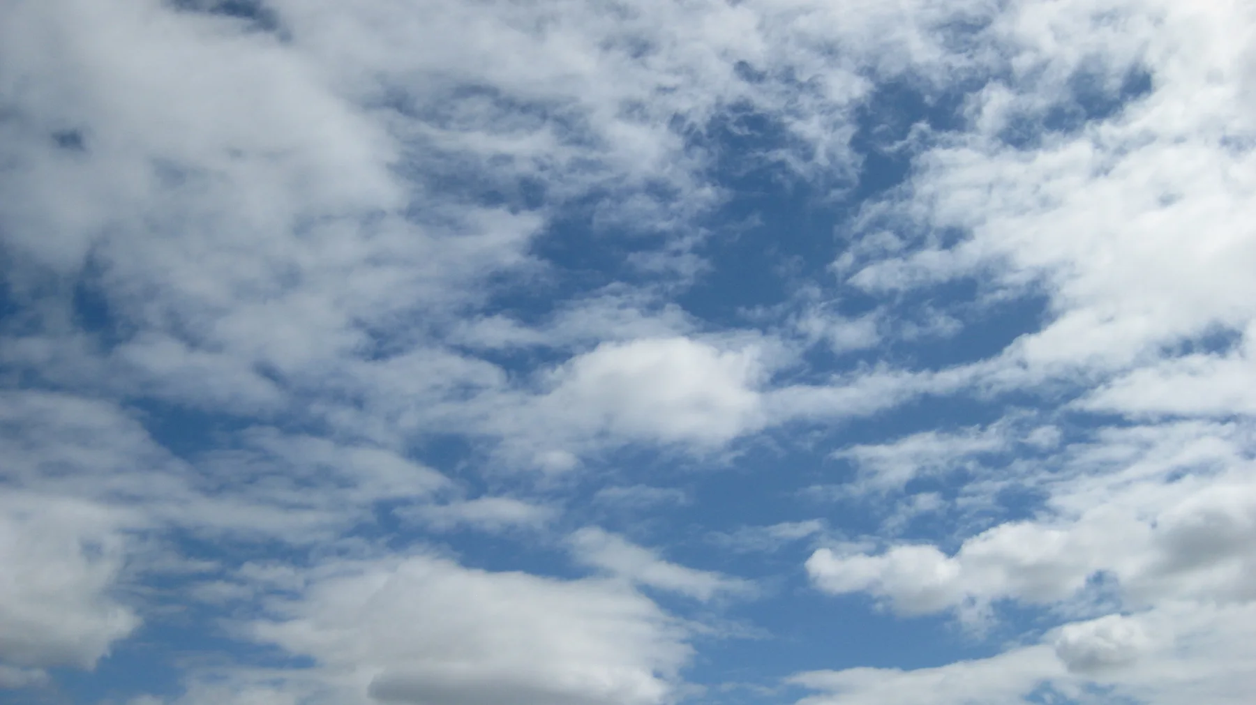 Broken white clouds surround blue openings overhead.