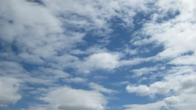 Broken white clouds surround blue openings overhead.