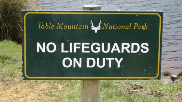 A green sign beside water reads No Lifeguards on Duty.
