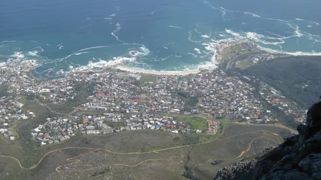 Several curved bays and dense buildings lie below a broad mountain slope.