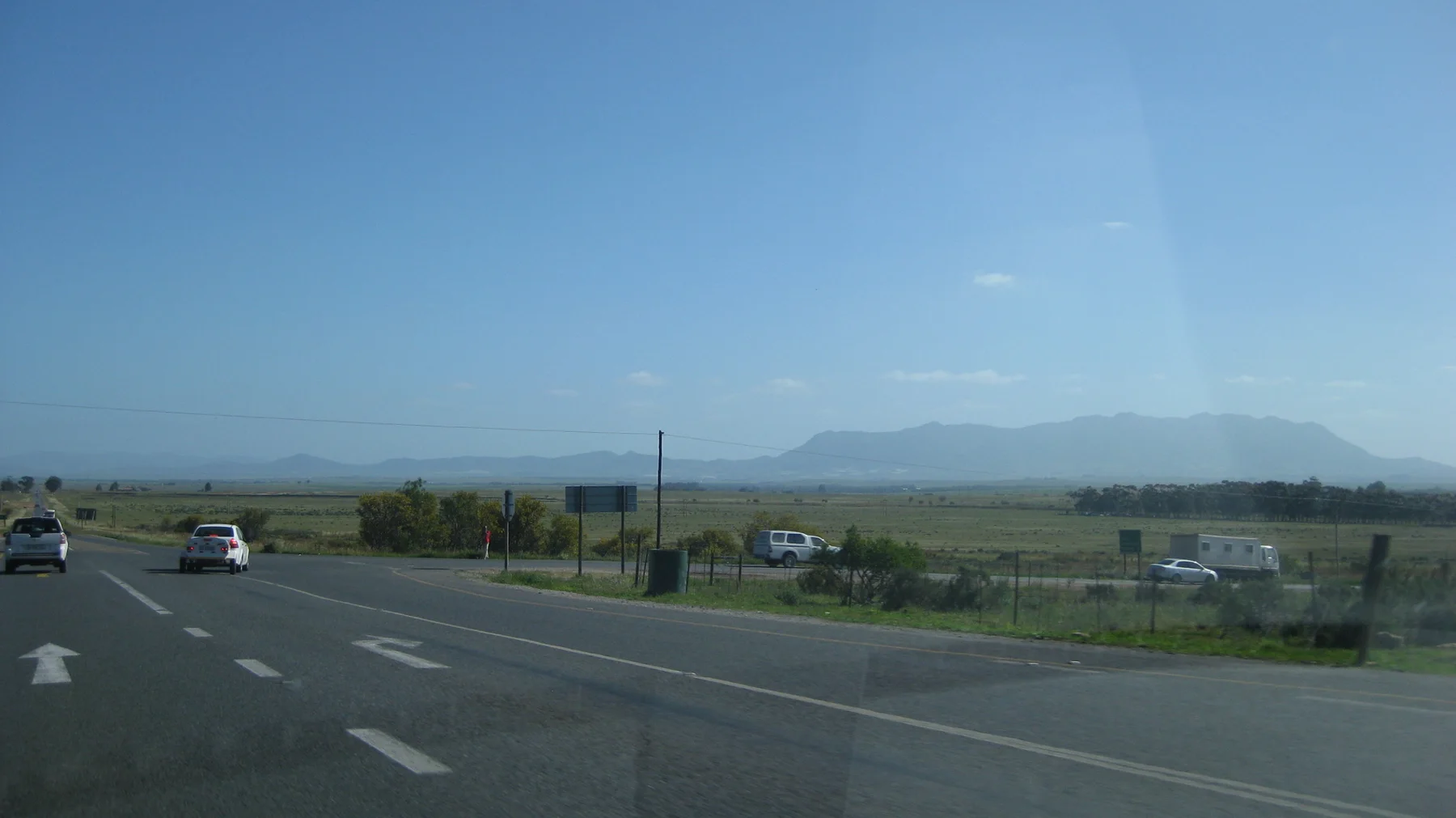 Road arrows and vehicles mark a junction across open countryside.