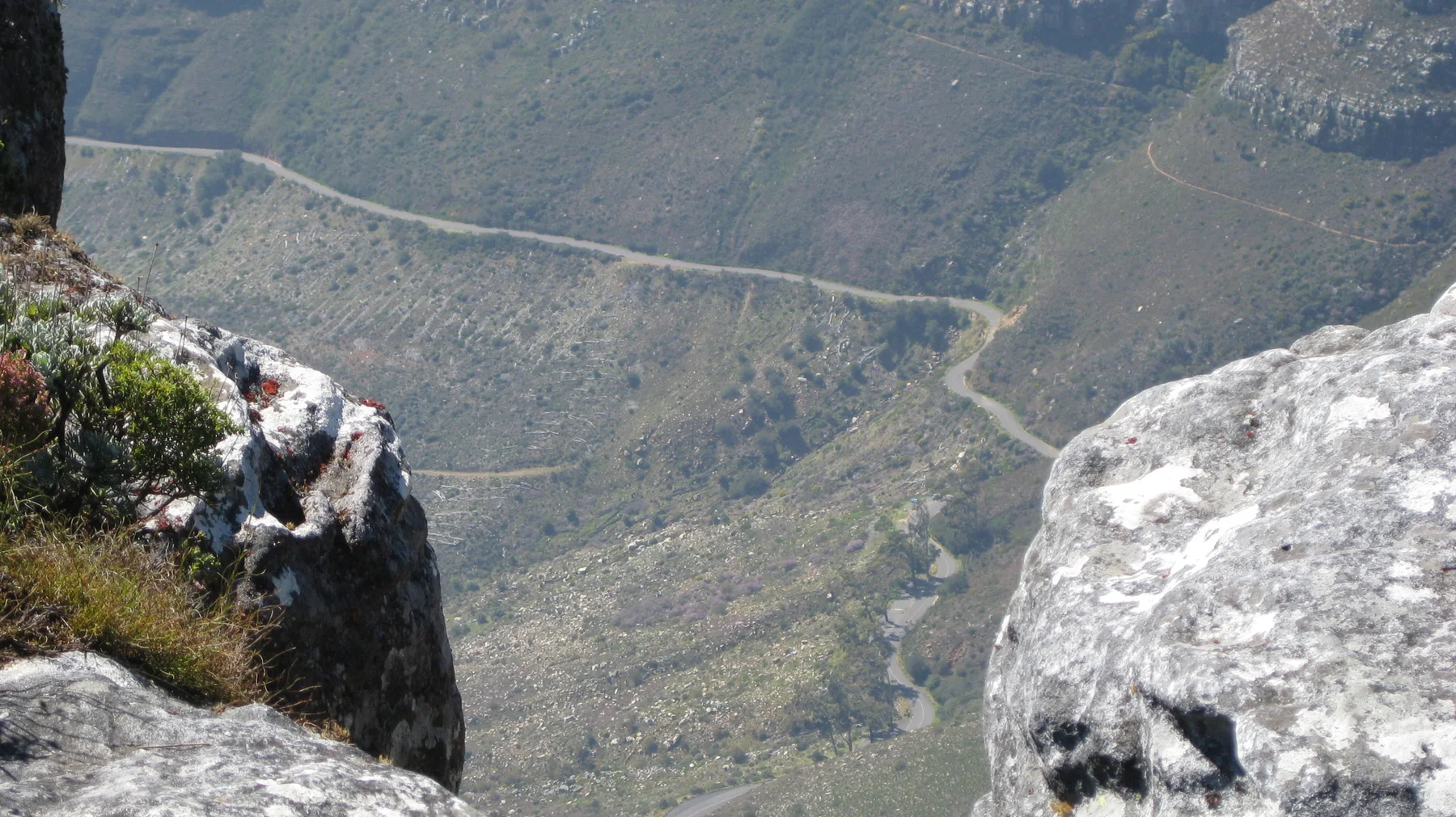 A narrow road snakes across a steep mountainside far below the lookout.