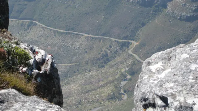 A narrow road snakes across a steep mountainside far below the lookout.