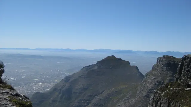A dark peak rises above a hazy developed valley.