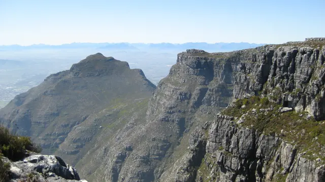 A pointed peak rises beyond a deep gorge and sheer cliff.