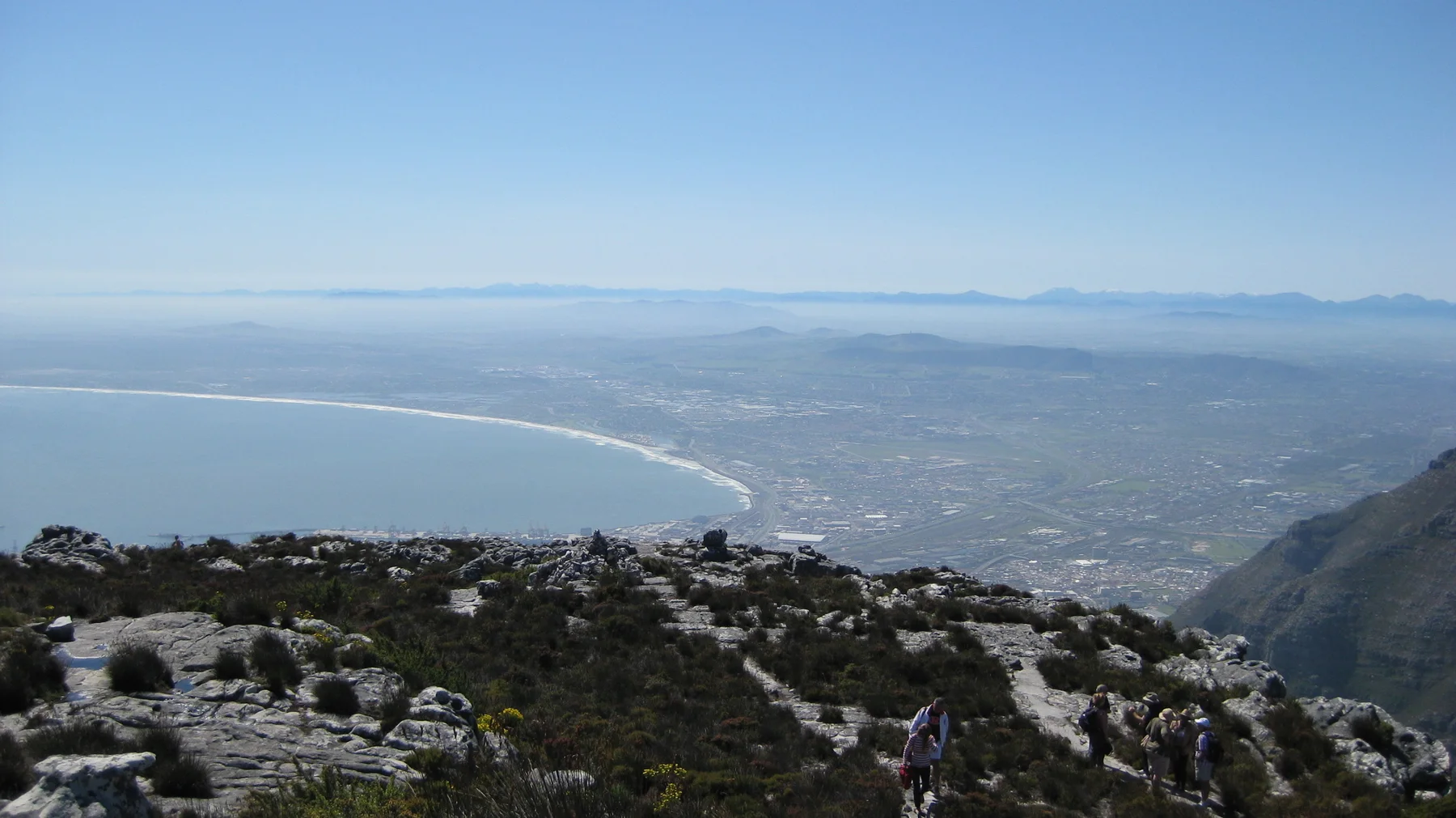 A broad curved bay lies beyond a rocky summit plateau.