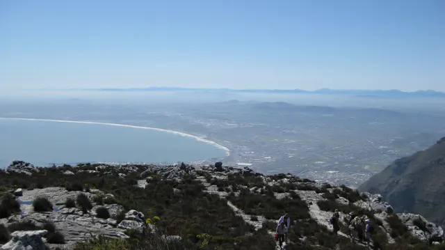 A broad curved bay lies beyond a rocky summit plateau.