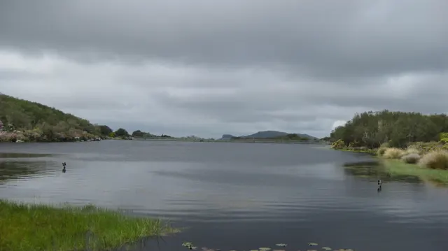 Broad reservoir water stretches beneath a heavy gray sky.