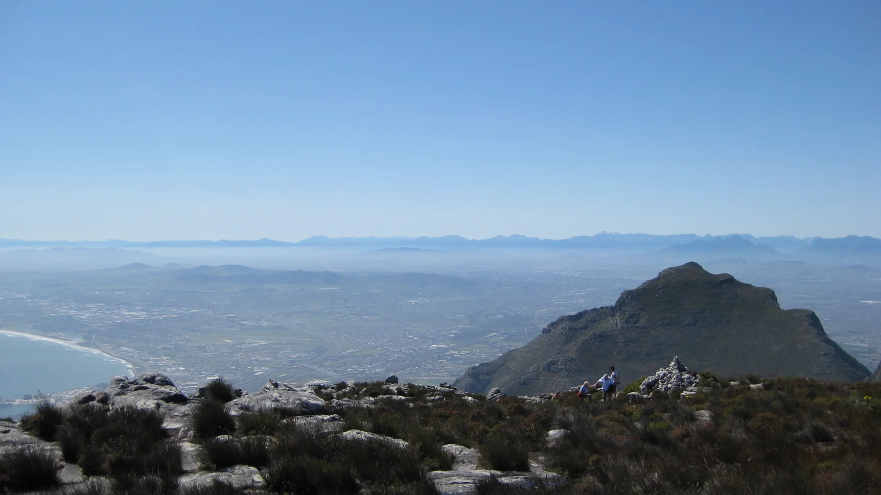 Summit stones overlook a hazy valley and a prominent dark peak.