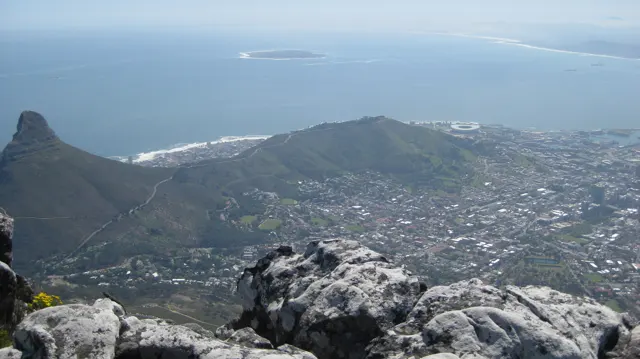 Pointed hills rise above the city beside the blue ocean.