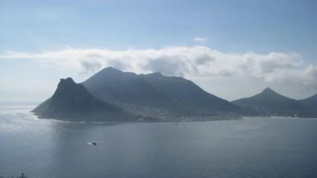 A dark headland and higher mountains rise across calm water.