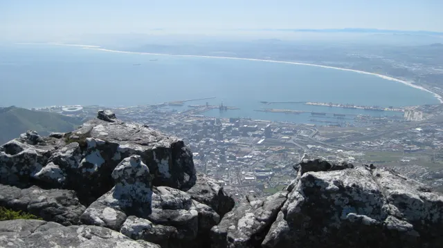 Rough summit rocks overlook a harbor and sweeping bay.