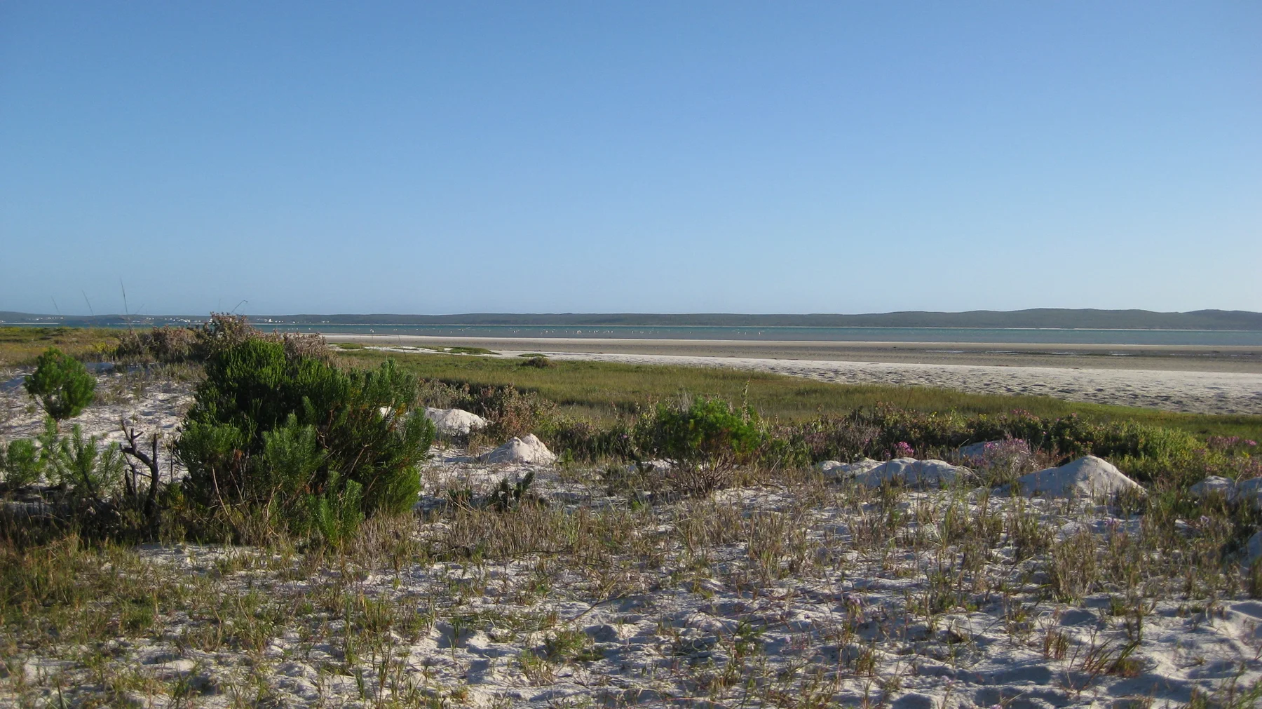 Low rocky scrubland stretches toward a flat distant shoreline.