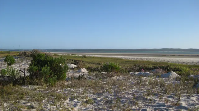 Low rocky scrubland stretches toward a flat distant shoreline.
