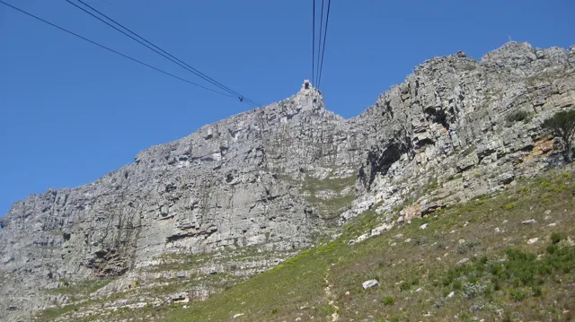 Cable lines climb toward a pale rocky summit under clear sky.
