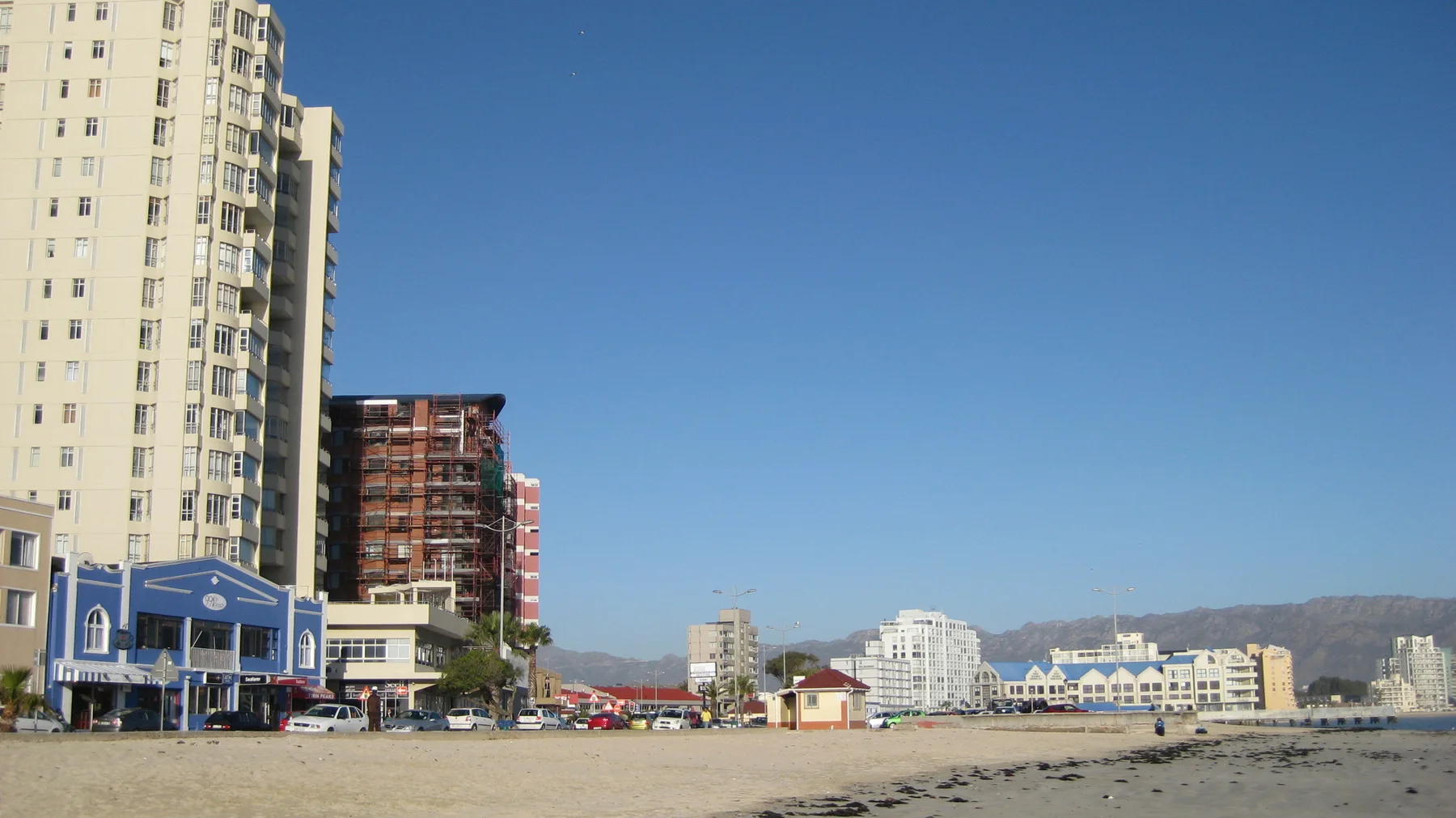 Tall apartment buildings stand beside a broad sandy beach.
