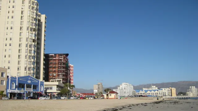 Tall apartment buildings stand beside a broad sandy beach.