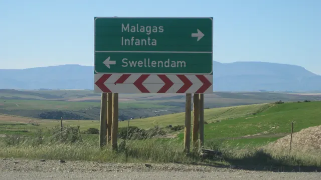 A green sign points toward Malagas, Infanta and Swellendam beside fields.