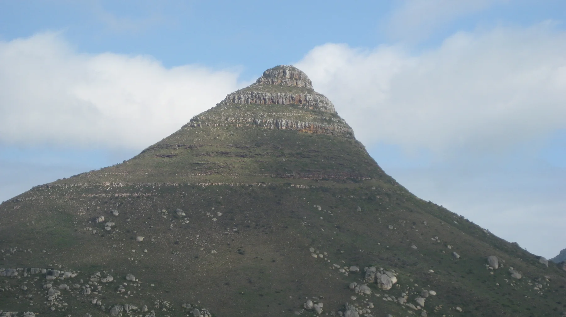 A steep pointed summit rises above a dark green slope.