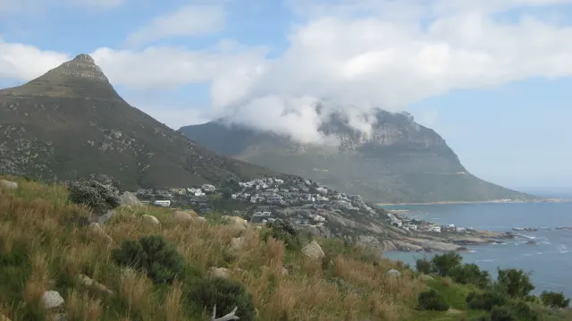 Pointed coastal peaks rise above hillside houses beneath drifting cloud.