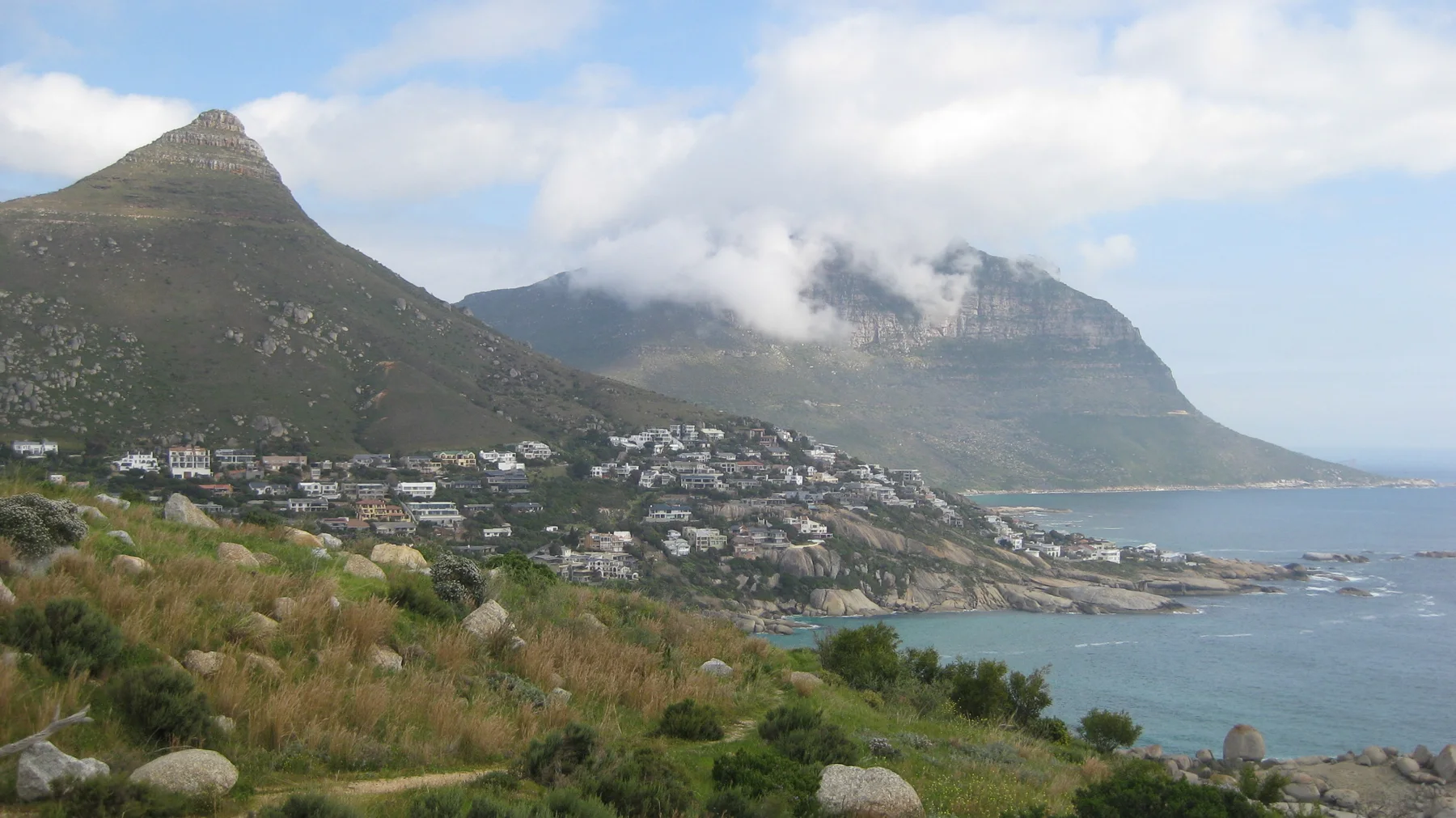 White houses spread below a pointed peak beside the coast.