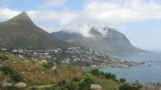White houses spread below a pointed peak beside the coast.