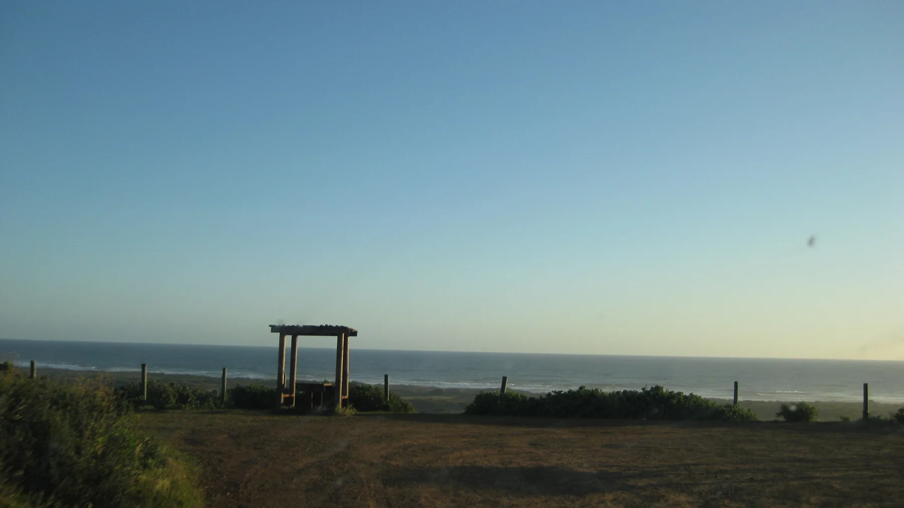 A simple wooden frame stands at a quiet lookout above the sea.