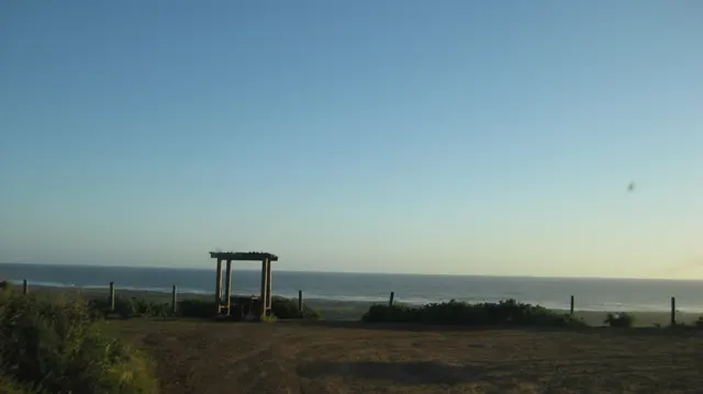 A simple wooden frame stands at a quiet lookout above the sea.