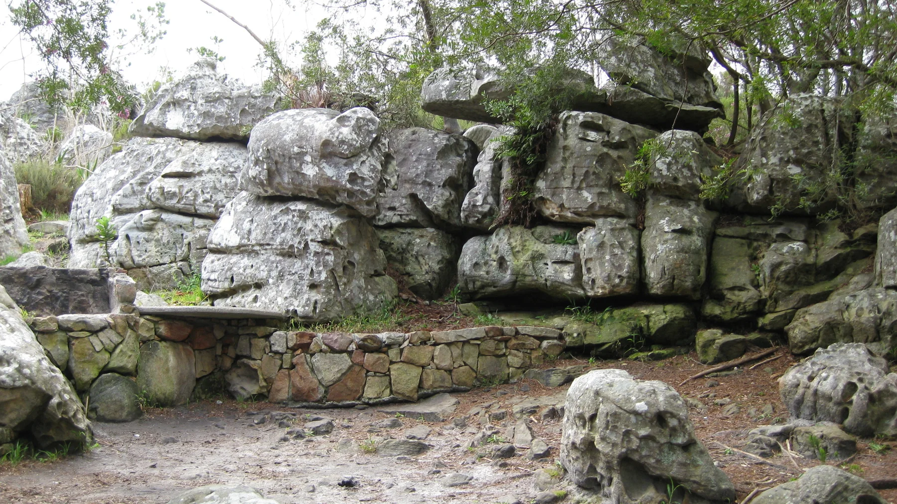 A low stone seat rests beneath large layered boulders.