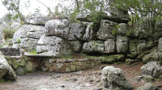 A low stone seat rests beneath large layered boulders.