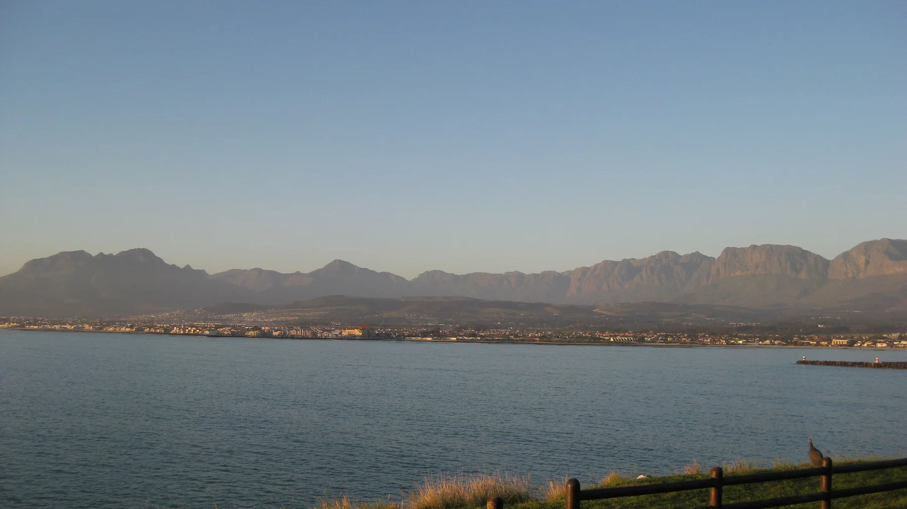A long mountain range stretches across calm blue water.