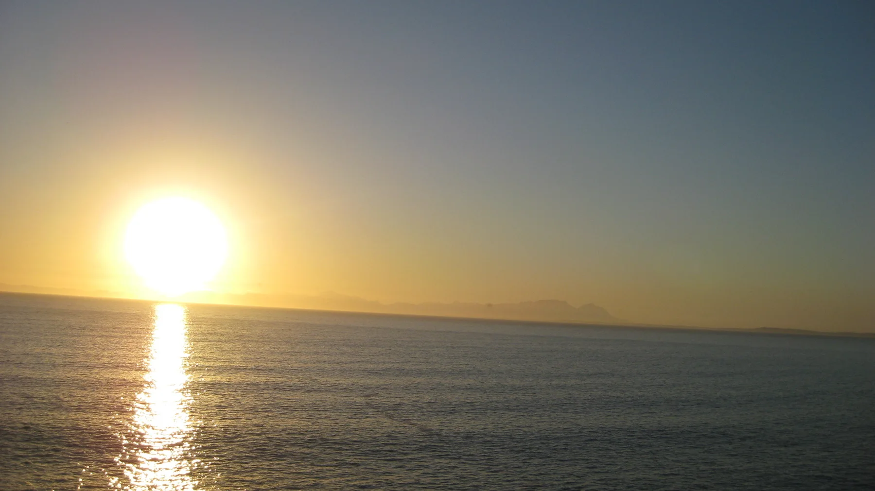The low sun draws a bright golden line across calm water.