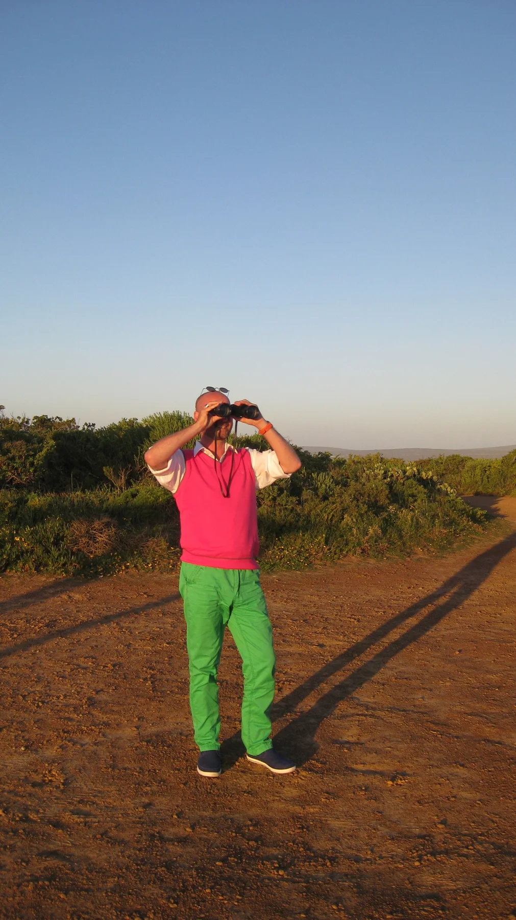 A person in pink and green clothing holds a camera at a lookout.