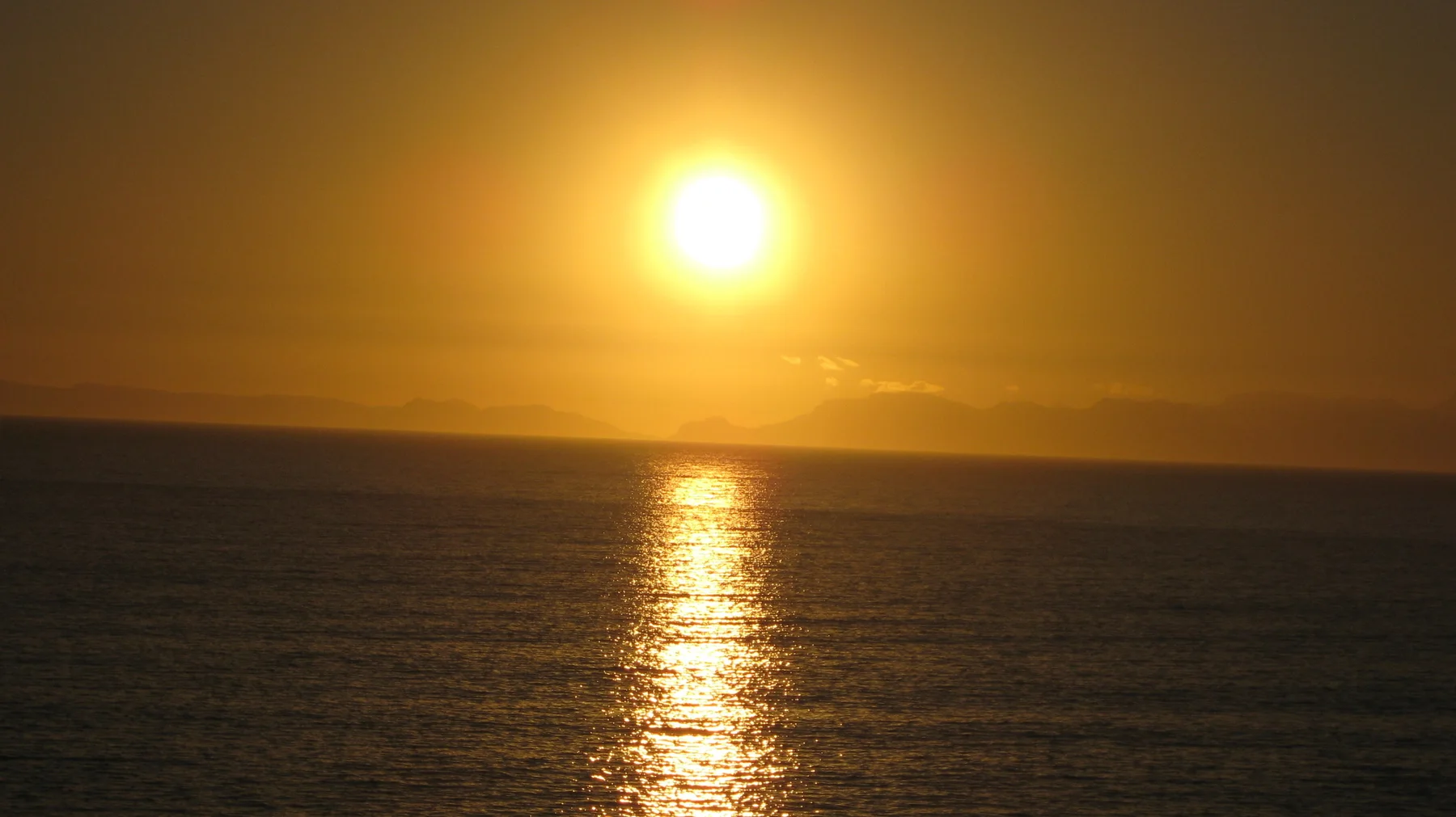 An orange sun glows above a shimmering vertical reflection.