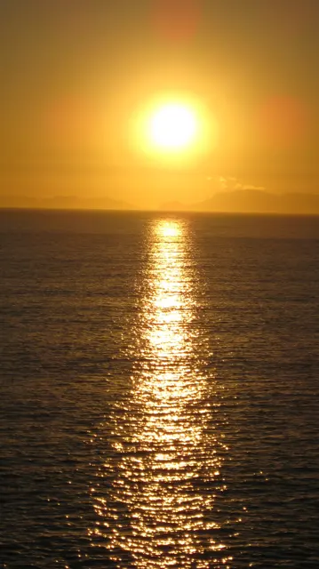 A narrow golden reflection reaches across rippled dark water.