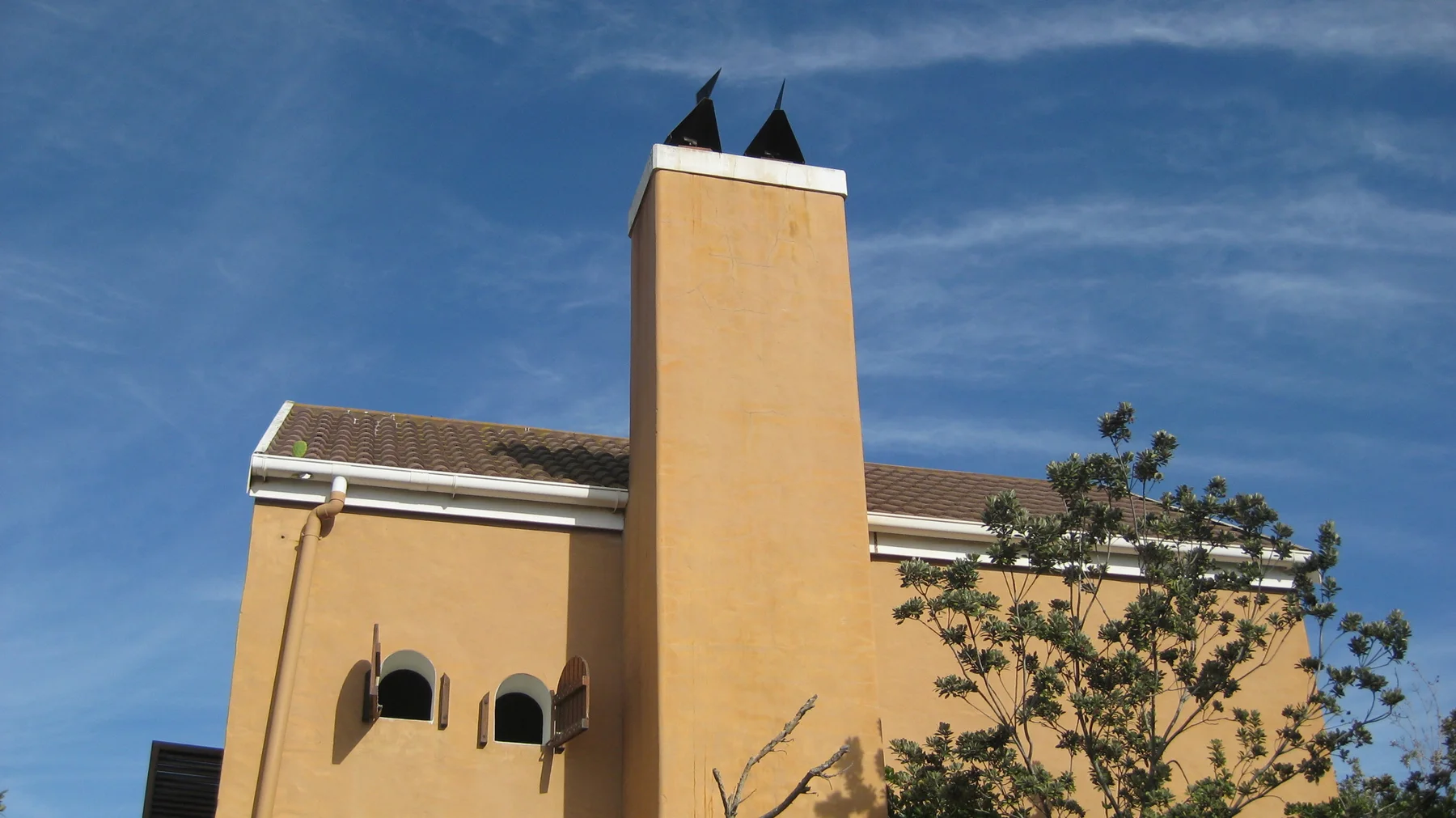 A tall ochre building tower rises against deep blue sky.