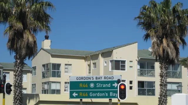 Road signs near traffic lights indicate Strand and Gordon's Bay.