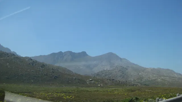 A rocky mountain range rises beyond low green scrub.