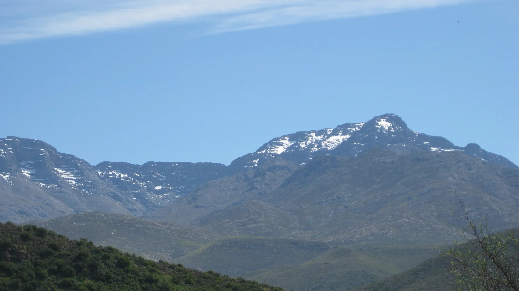 White snow patches lie near the tops of a dark mountain ridge.
