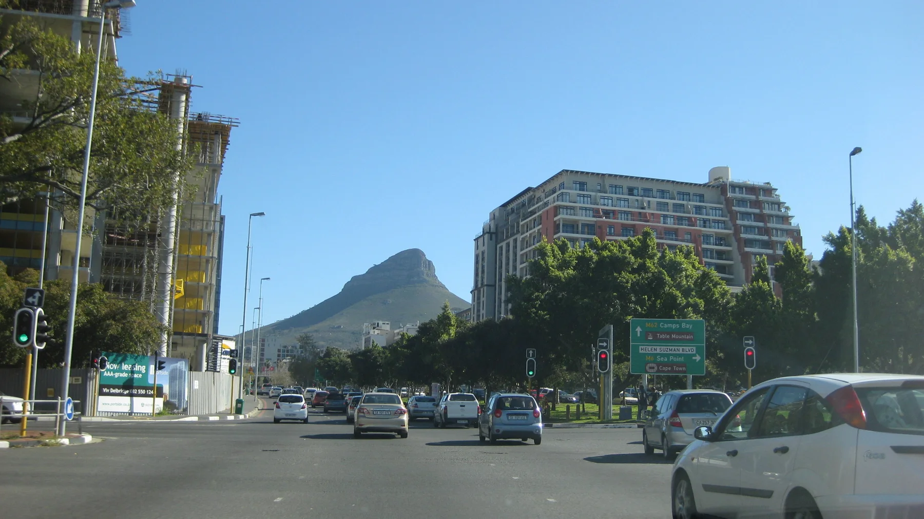 Traffic crosses a broad intersection with a pointed hill beyond.