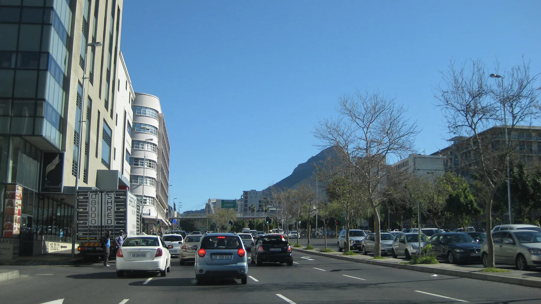 A street runs between tall buildings toward a distant pointed hill.