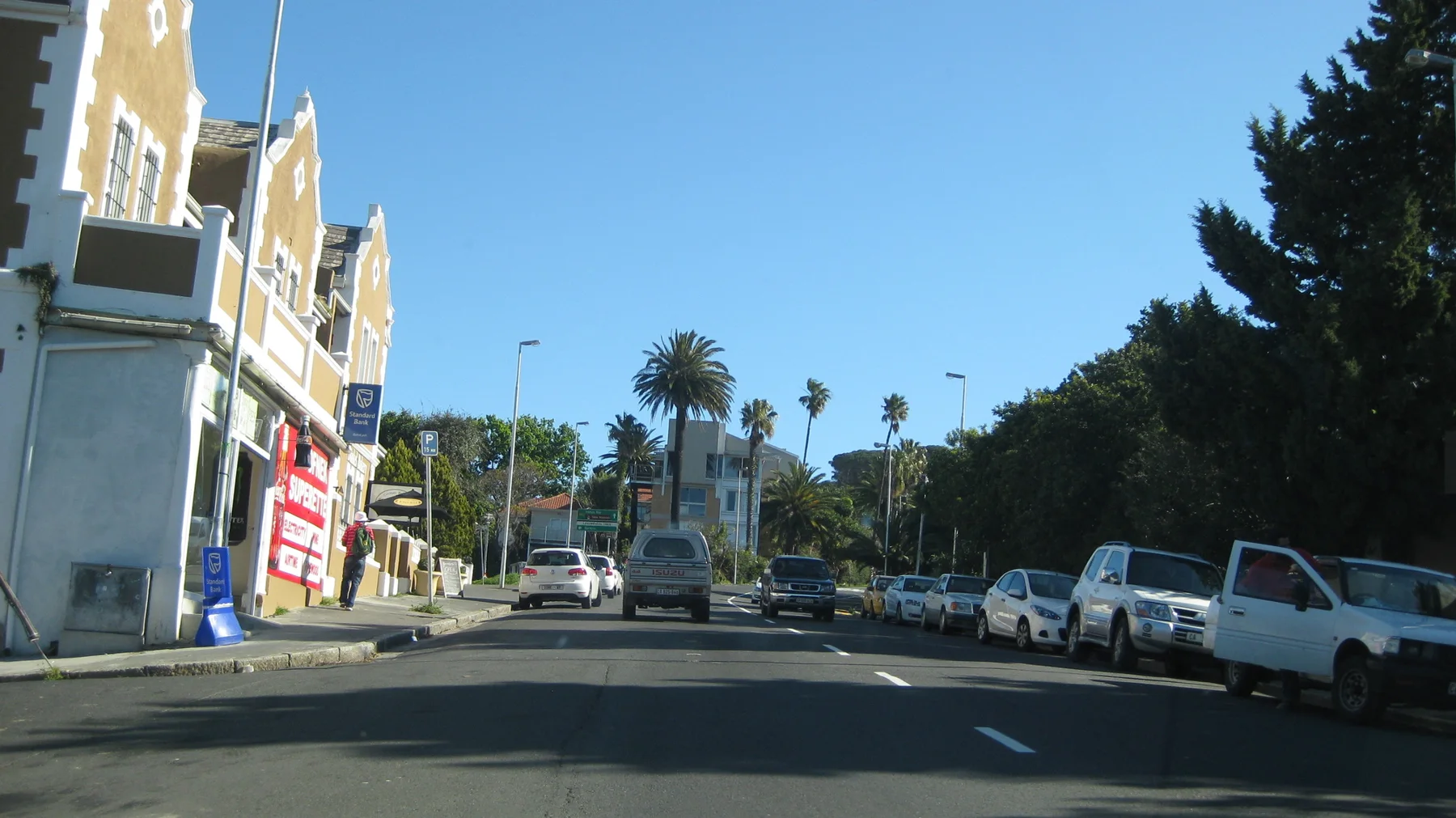A decorated pale facade stands beside traffic and tall palms.