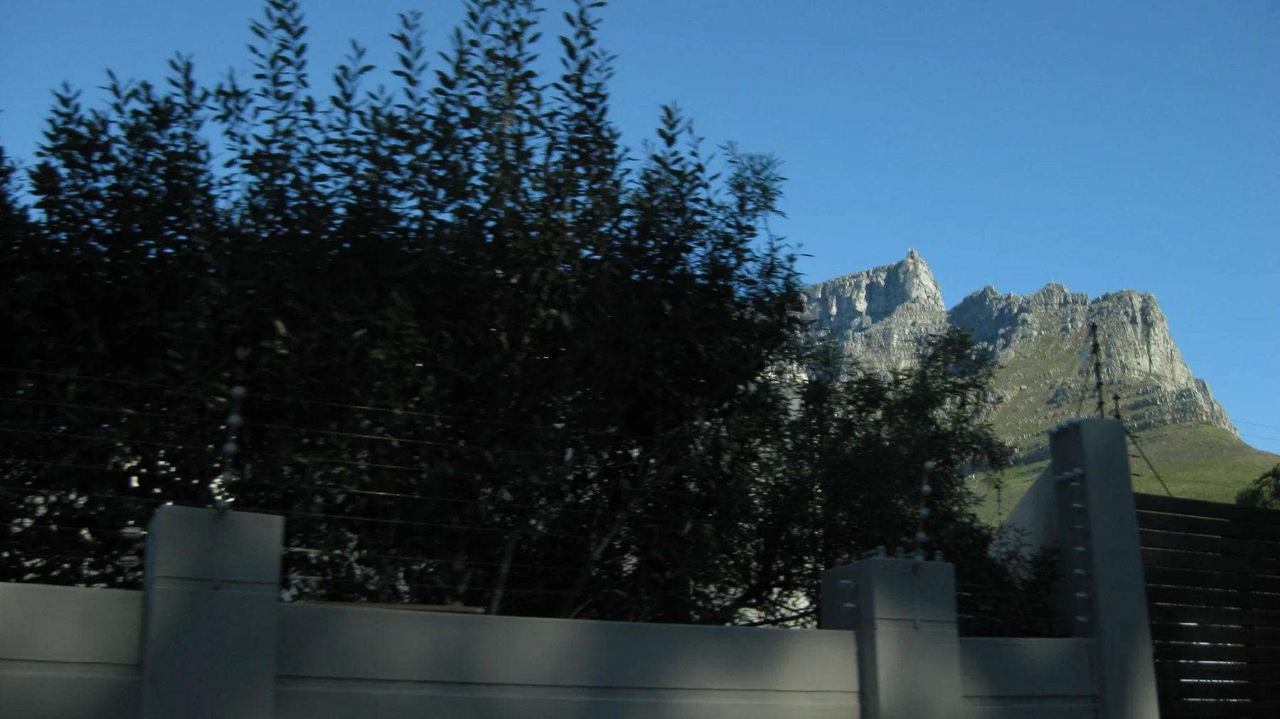 A rocky peak appears above dark trees and a garden wall.