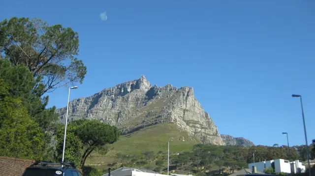 Rocky peaks rise above trees and low neighborhood buildings.