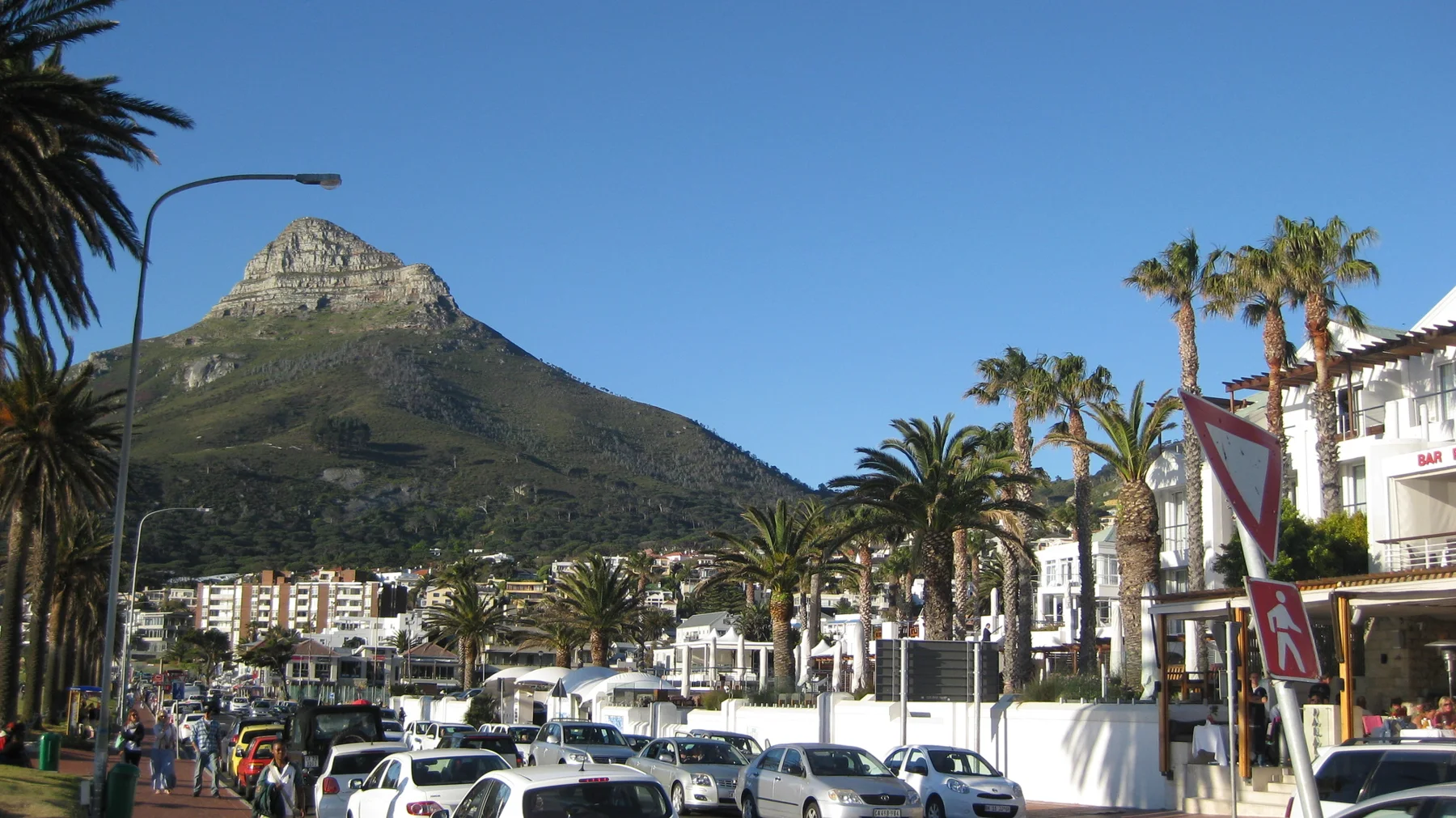 A pointed peak rises behind white shops and busy traffic.