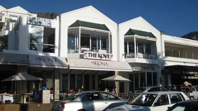 A white restaurant facade marked The Kove faces parked cars.