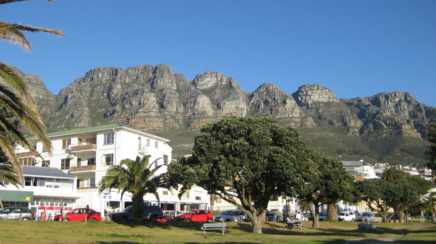 White buildings and trees sit below a long rocky ridge.