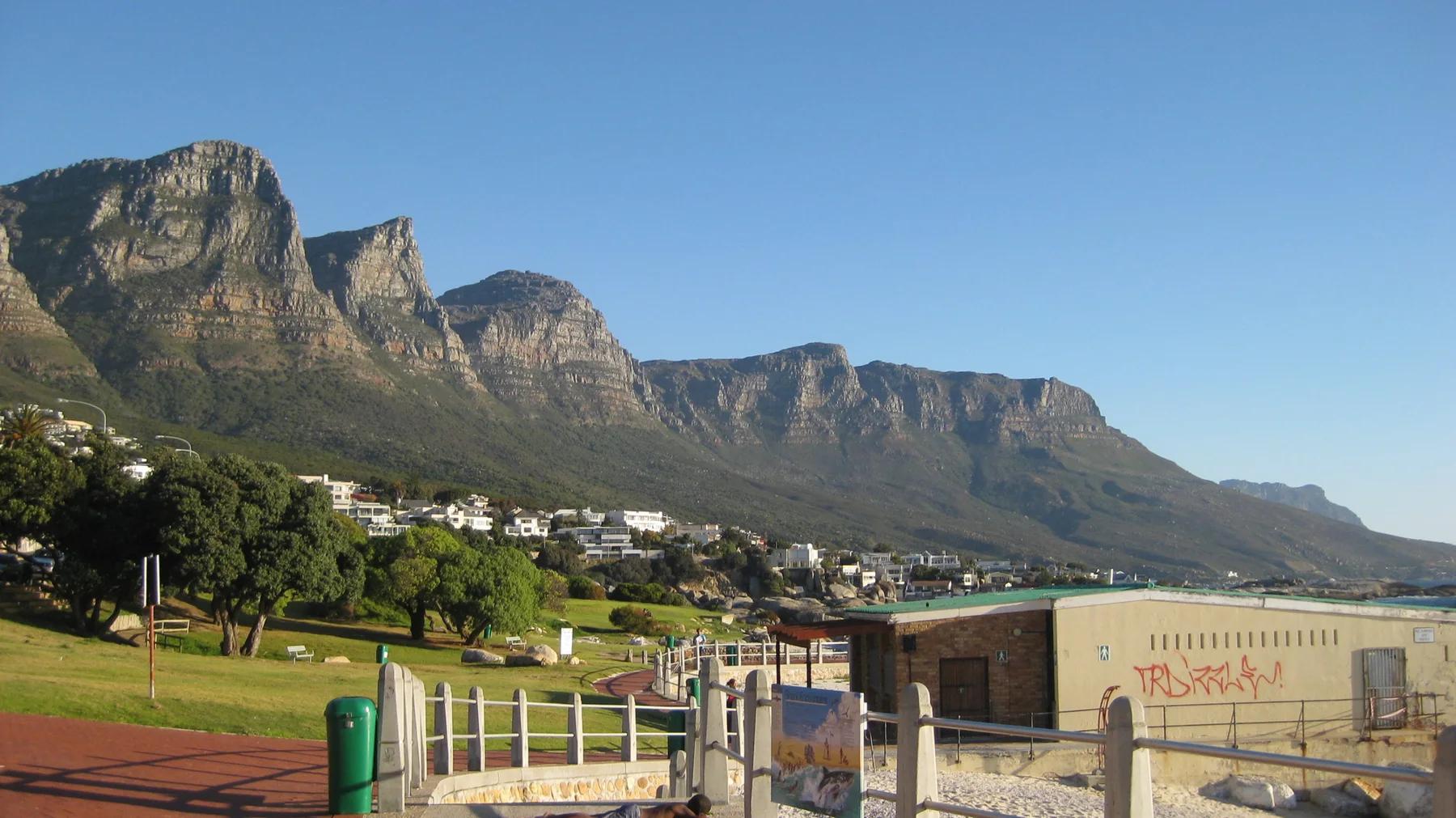 Railings and low walls border a promenade beneath mountains.