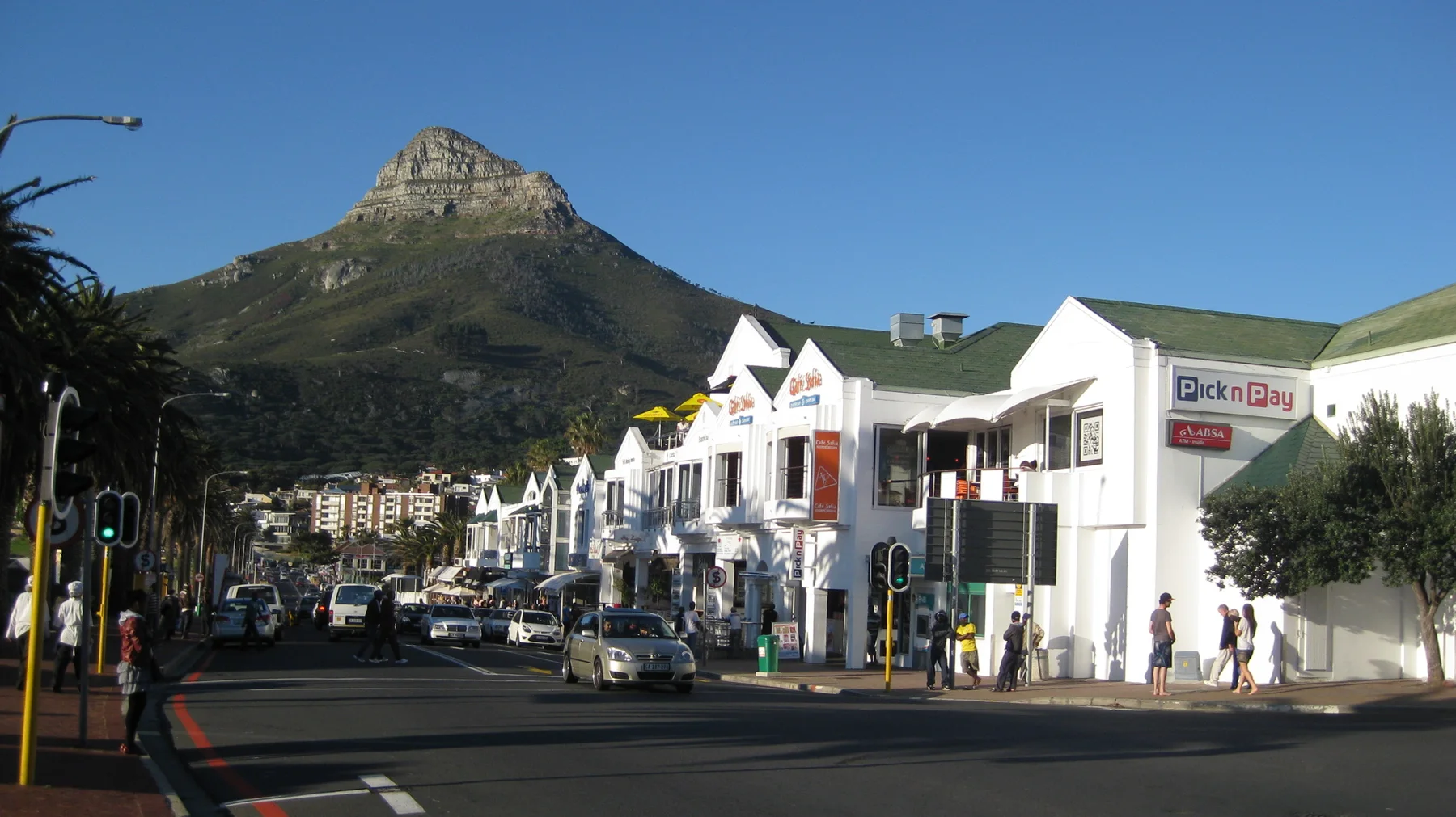 A shop-lined street leads toward a distinctive pointed mountain.