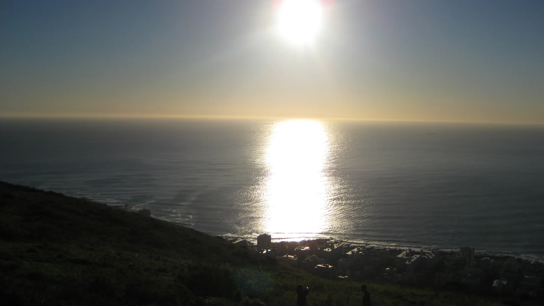 A bright sun casts a wide silver reflection across the ocean.
